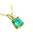 A yellow gold pendant with an emerald-cut natural colombian emerald displaying the topside.