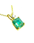 A yellow gold pendant with an emerald-cut natural colombian emerald displaying the topside.