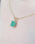 Gold necklace with a Muzo colombian emerald pendant on a person's neck.