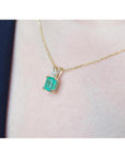 Gold necklace with a Muzo colombian emerald pendant on a person's neck.