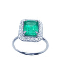 Radiant emerald-cut bluish-green emerald ring with halo diamonds in 14K white gold.