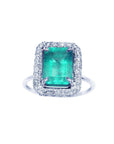 A square emerald-cut emerald ring for women encircled by a halo diamond in 18k white gold.