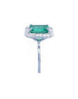 Emerald-cut bluish-green emerald ring with halo diamonds in 14K white gold.