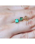 Square emerald stud earrings in 14K yellow gold, featuring octagonal cut green emeralds.