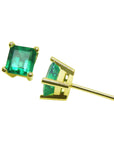 A pair of 14K gold emerald stud earrings placed on a front and side positions profile's view.
