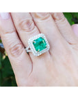 4.14 ct GIA F1 Colombian emerald ring with diamond halo and band in 14K white gold on a hand.