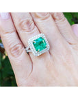 4.14 ct GIA F1 Colombian emerald ring with diamond halo and band in 14K white gold on a hand.