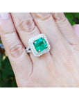 4.14 ct GIA F1 Colombian emerald ring with diamond halo and band in 14K white gold on a hand.