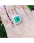 4.14 ct GIA F1 Colombian emerald ring with diamond halo and band in 14K white gold on a hand.