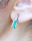 Close-up of an ear wearing a natural emerald stud earring.