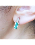 Baguette emerald and diamond stud earring in 14k white gold, worn on an ear.