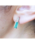 Baguette emerald and diamond stud earring in 14k white gold, worn on an ear.
