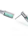 Pair of white gold earrings with emerald rectangular stones, underside view with right profile.