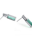 Pair of white gold earrings with emerald rectangular stones, underside view with right profile.