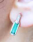 Close-up of a natural emerald stud earring being worn.