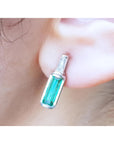 14k white gold stud earring with a baguette emerald and diamond accent, shaped like a miniature bottle.