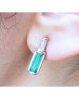 14k white gold stud earring with a baguette emerald and diamond accent, shaped like a miniature bottle.