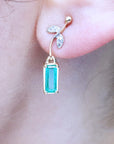 Close-up of a emerald-cut emerald earrings on an ear with a blurred background