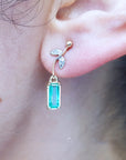 Close-up of an ear wearing a 14k yellow gold emerald earring