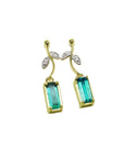Front position of a pair of emerald dangle earrings in 14k yellow gold, pending from a leafy stem