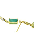 Underside profile view of a pair of 14k yellow gold emerald earrings push backs