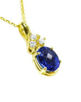 14K yellow gold pendant with a deep blue oval tanzanite and three sparkling diamonds.