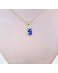 14K yellow gold pendant with an oval tanzanite and three diamonds on a woman's neck.