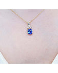 14K yellow gold pendant with an oval tanzanite and three diamonds on a woman's neck.