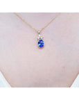 14K yellow gold pendant with an oval tanzanite and three diamonds on a woman's neck.