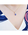 14K yellow gold pendant with oval tanzanite and three diamonds on a woman's neck.