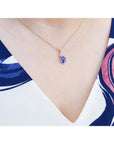 14K yellow gold pendant with oval tanzanite and three diamonds on a woman's neck.