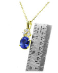 14K yellow gold tanzanite pendant with three diamonds, next to a ruler.