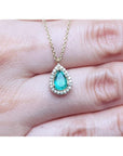 Pear-shaped natural emerald necklace with diamond halo in 14K yellow gold.