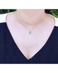 Pear-shaped natural emerald necklace with diamond halo, 14K yellow gold, worn on a woman.
