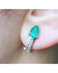Pear-shaped emerald clip-on earring with accent diamonds in 14K white gold on an ear.