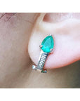 Pear-shaped emerald clip-on earring with accent diamonds in 14K white gold on an ear.