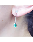 Emerald dangle earrings with pear-shaped Muzo emeralds and diamonds in 14K white gold.