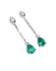 Pair of teardrop emerald dangle earrings on a right-side position top view.