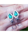 14K white gold clip/post earrings with pear-shaped Colombian emeralds and diamond accents.