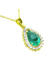 Gold pendant with a teardrop-shaped natural emerald surrounded by a halo of genuine diamonds
