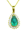 The topside view of a teardrop natural colombian emerald pendant encircled by a halo of natural diamonds in yellow gold.