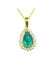 The topside view of a teardrop natural colombian emerald pendant encircled by a halo of natural diamonds in yellow gold.