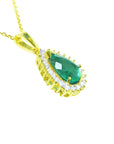 A yellow gold necklace with a natural teardrop emerald pendant on a white background