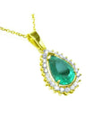 Gold pendant with a teardrop-shaped natural emerald surrounded by a halo of genuine diamonds.