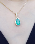Teardrop-shaped natural emerald pendant on a gold chain on a woman's neck