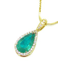 Teardrop-shaped emerald pendant with gold frame and diamond accents on a white background