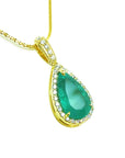 Gold necklace with a natural emerald teardrop pendant topside view on a white background