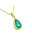 Gold necklace with a natural emerald teardrop pendant topside view on a white background