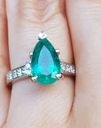 A Colombian emerald teardrop natural gemstone ring on a hand.