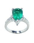 A white gold ring with a natural emerald on top and down shank profile.